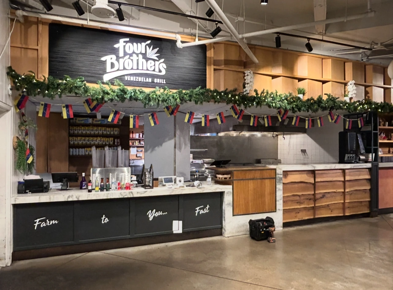 Four Brothers’ Congress Avenue counter with wood cabinetry and a large black sign above it.