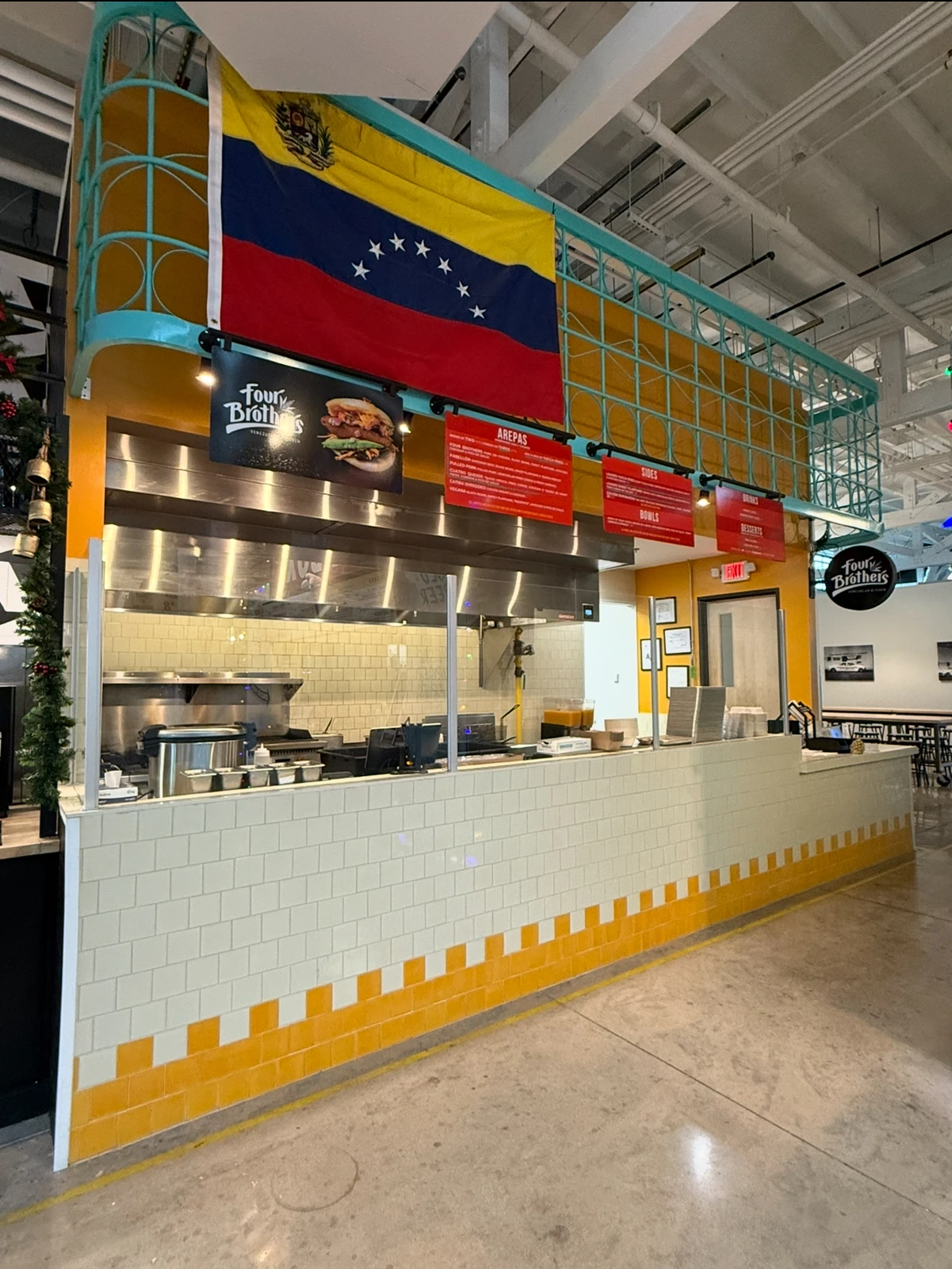 Four Brothers’ San Antonio counter beneath a Venezuelan flag, with teal metalwork and yellow-and-white tile details.